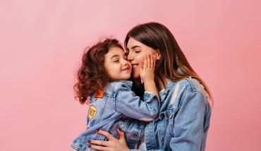 Mamá joven besando a su hija y aprovechando los PUNTOS de la Proveeduría de la Mutual del Club Atlético Pilar